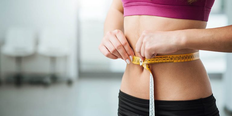 Person measuring waist with tape in fitness gear, healthy lifestyle concept.