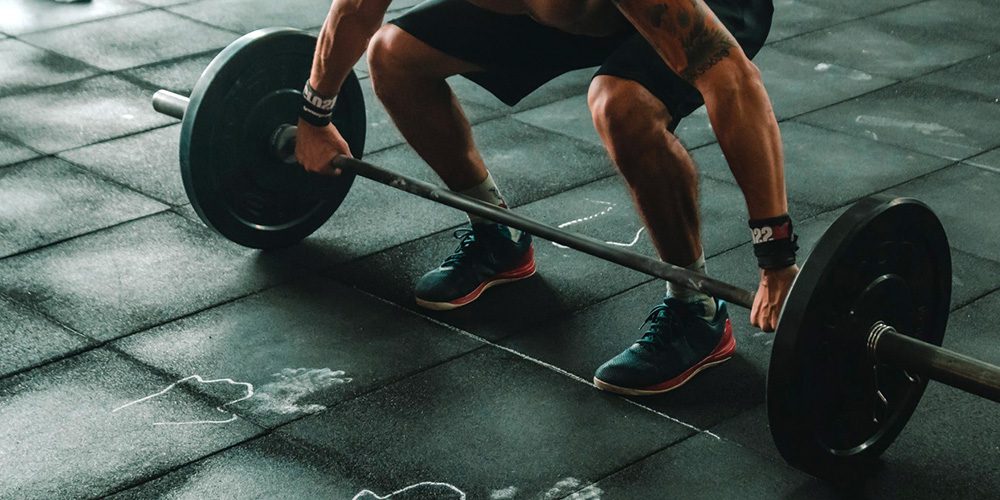Man lifts barbell in the gym, focused on strength training and fitness.