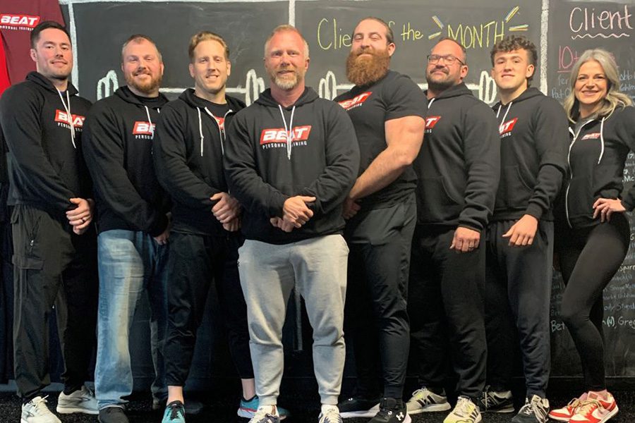 Group of trainers at BEAT Personal Training gym in front of chalkboard wall.