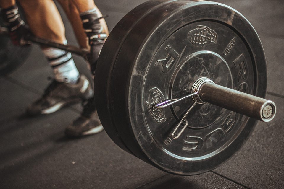 Person lifting heavy barbell in gym.
